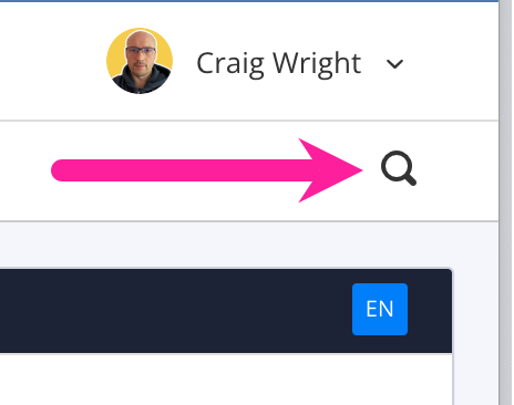 Close-up of top-right corner of editor. There is a user avatar and name and below it a magnifying glass search icon. A callout arrow points to the magnifying glass search icon.
